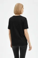 Remera negra de algodón con cuello redondo, manga corta y estampa frontal con texto en blanco.