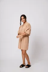 Vestido corto color tostado, con cuello solapa, abotonado al frente y mangas 3/4 con puños fruncidos.