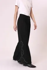 Pantalón palazzo negro con bordado de pequeñas tachas plateadas en forma de rombos a lo largo de la pierna.