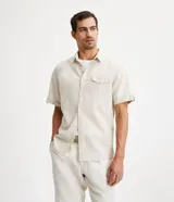Camisa de corte comfort confeccionada en mezcla de lino y algodón, con cuello inglés, cierre frontal de botones, manga corta con dobladillo y un bolsillo frontal aplicado.