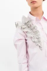 Camisa rosa pálido de manga larga con cuello camisero y volados grises en el frente y los puños.