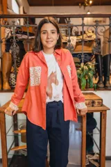 Sobre camisa coral de manga larga, con canesú en la espalda y detalles en los puños de tela estampada con flores.