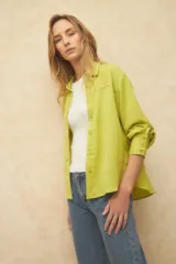 Camisa blanca de manga larga con textura arrugada, cuello camisero y botones frontales. Presenta un corte holgado y puños anchos con tres botones.