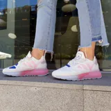 Championes urbanos Adidas ZX 2K Boost para mujer, color blanco con detalles en rosa y plateado. Inspirados en la misión espacial Artemisa, con mediasuela Boost y detalles metalizados.