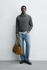 Polo de manga larga color gris oscuro, con diseño de textura estructurada, cuello solapa y cierre frontal de cremallera corta. Cuenta con puños y cintura de rib elástico.