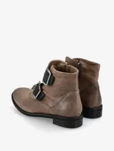 Bota corta marrón de cuero con dos correas con hebillas metálicas en la parte delantera y cierre lateral.