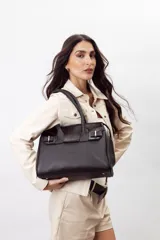 Cartera de mano estructurada de cuero vacuno rojo, con doble asa superior y detalles de charol en la parte superior. Cuenta con cierres metálicos y apliques decorativos laterales con hebillas.