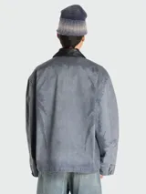 Campera de estilo urbano con efecto desgastado, confeccionada en tejido gris con acabado lavado. Presenta cuello de cuero negro en contraste, cierre frontal con cremallera y diseño de corte holgado.