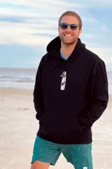 Canguro negro con capucha y cordones ajustables, bolsillo tipo canguro y puños y cintura acanalados. Estampado de tabla de surf con texto en el pecho.