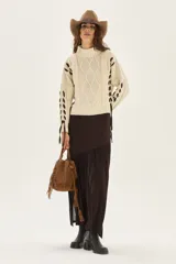 Polera de tejido de punto con diseño de ochos y detalles de tientos en contratono en las mangas. Presenta cuello alto y corte cropped.