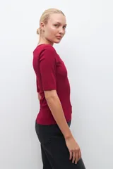 Remera verde de tejido canalé con cuello redondo y media manga. Tiene una abertura frontal con botones.