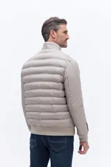 Campera puffer de nylon color beige, con diseño minimalista, cuello alto, cierre frontal y puños elásticos. Presenta logo de la marca bordado en el pecho.