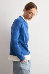 Sweater clásico de punto color beige, de cuello redondo y manga larga con diseño ajustado.
