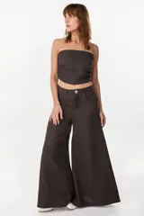 Pantalón de lino verde militar, de tiro alto y corte amplio con botamanga ancha. Cuenta con bolsillos delanteros aplicados y cierre frontal con botón y bragueta.