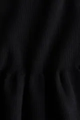 Top de punto acanalado entallado, con escote bote, mangas largas y detalle de peplum con vuelo en la cintura.