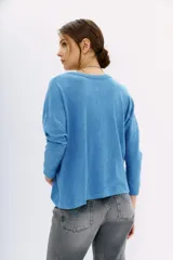 Remera azul de algodón peruano con textura jaspeada, de moldería holgada y buena caída, con mangas largas que se ajustan hacia la muñeca y se ensanchan debajo del brazo.