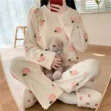 Conjunto de pijama de dos piezas confeccionado en plush suave, compuesto por una remera de manga larga y pantalón largo. Presenta un diseño estampado de duraznos sobre fondo color crema.