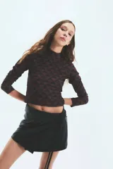 Polera marrón con estampado geométrico de triángulos y monogramas. De cuello alto y mangas largas.