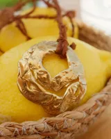 Collar artesanal con dije de flor en bronce o alpaca, suspendido en un cordón de seda natural teñido a mano. El diseño permite atarse con un moño, ofreciendo versatilidad para lucirlo de distintas formas.