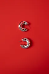 Aros tipo argolla de diseño chunky, con acabado plateado brillante y forma redondeada.