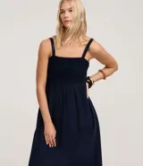 Vestido midi de corte evasé en color azul marino, confeccionado en una mezcla de algodón y lino. Presenta un escote cuadrado con tirantes anchos y un detalle de tejido con efecto crochet en la zona del busto.