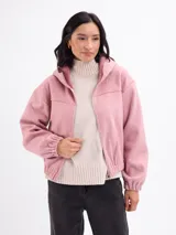Campera de paño color beige con capucha, cierre frontal completo y mangas largas con puños elásticos. Presenta un diseño corto con ruedo elástico.