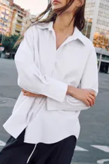 Camisa básica de corte recto y diseño minimalista, confeccionada en tejido de algodón. Presenta cuello solapa, escote en pico, cierre frontal con botones y mangas largas con puños abotonados.