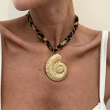 Collar tipo choker con cinta trenzada con estampado de leopardo y un dije grande de cruz dorada con textura martillada.