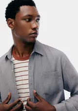 Camisa de manga larga en color gris, con cuello clásico, cierre frontal de botones y un bolsillo en el pecho.