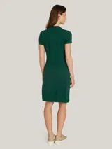 Vestido verde de piqué de algodón orgánico elástico, corte slim, cuello tipo chomba, cartera de 5 botones y logo de Tommy Hilfiger bordado en el pecho.