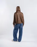 Campera cropped tipo bomber color marrón con acabado vintage, capucha con cordón ajustable, cierre frontal y puños y ruedo elásticos.