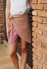 Minifalda cruzada color rosa con textura brillante y lazo lateral.