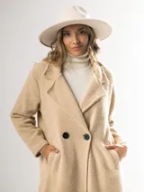 Tapado clásico color beige, con solapas de muesca, doble botonadura y bolsillos laterales.