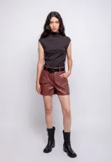 Short de cuero sintético color marrón óxido, de tiro alto, con bolsillos laterales y traseros. Incluye cinturón de cuero negro con hebilla cuadrada.