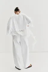 Camiseta de algodón con cuello redondo y manga corta. Presenta un bajo asimétrico confeccionado en un tejido ligero con volantes y una tira lateral decorativa con volantes.