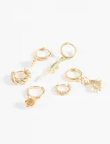 Set de aros plateados con diferentes dijes: argollas con concha de mar, argolla con cocodrilo, argolla con concha de abanico, argolla trenzada, argolla con piedra.