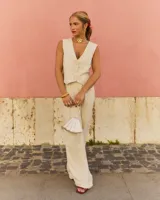 Pantalón de vestir color beige, de corte recto y talle alto, con pinzas frontales y cierre con cremallera, botón y gancho metálico.