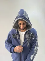 Campera reversible con cierre frontal. Un lado confeccionado en algodón azul marino con estampa plastisol, bordados con apliques y capucha. El otro lado presenta un diseño de polar de pelo largo en color gris. Posee corte oversize, puños y ruedo acanalados.