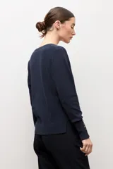 Cardigan negro con escote en V, manga larga y cierre frontal con botones pequeños. Presenta puños acanalados con detalle de botones decorativos.