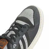 Championes adidas modelo Rivalry Low, con diseño de corte bajo. Presentan una combinación de paneles en cuero gris y denim oscuro con bordes deshilachados. Incluyen las icónicas tres tiras laterales en negro, suela de goma color crema y detalles en cuero marrón en la lengüeta y el lateral.