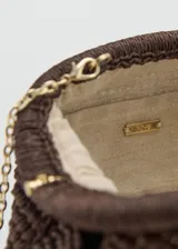 Bolso tipo clutch color marrón de tejido de fibra natural con diseño trenzado y nudo frontal. Cuenta con cierre de marco a presión y forro interior.