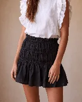 Minifalda de lino negra, con cintura fruncida y diseño de nido de abeja en la parte superior, con vuelo en el ruedo.