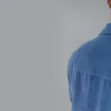 Camisa de pana azul con corte oversize, cuello clásico, cierre frontal de botones y dos bolsillos con solapa en el pecho.