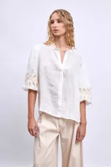 Blusa blanca de lino con cuello mao, mangas 3/4 abullonadas con apliques bordados en forma de hojas y cierre frontal con botones.
