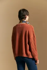 Cardigan de punto color terracota con diseño de trenzas verticales, cuello redondo y cierre frontal con botones metálicos. Presenta mangas largas con puños ajustados y un calce holgado.