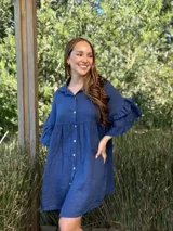 Vestido camisero blanco de lino italiano, con cuello camisero, cierre frontal con botones, mangas cortas con doble volado y bolsillos laterales.