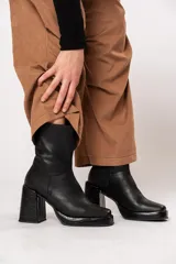 Bota de caña media color negro, de cuero, con horma cuadrada, taco geométrico con textura símil cocodrilo y plataforma.