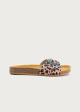 Sandalia plana con plantilla ergonómica y suela de corcho. Capellada de cuero con estampado animal print tipo leopardo y tira ancha ajustable con hebilla grande de resina translúcida en tono azulado.