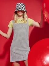 Vestido corto sin mangas de tela texturada con tirantes anchos y estampado a cuadros en blanco y negro.
