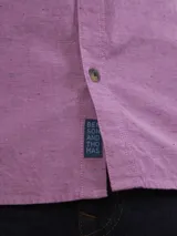 Camisa de manga larga color lila con cuello abotonado y bolsillo en el pecho.